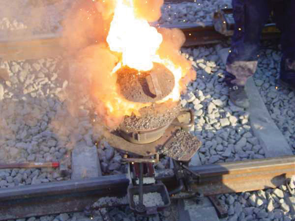 Pequeña olla de barro en llamas en vías del ferrocarril.
