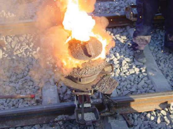 Small clay pot on fire on railroad tracks.