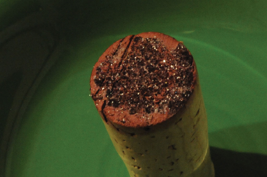 An inverted wine bottle cork is shown against a green background.